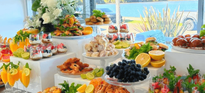 Wide event buffet with seafood, fruit, mocktails, and layered serving pieces