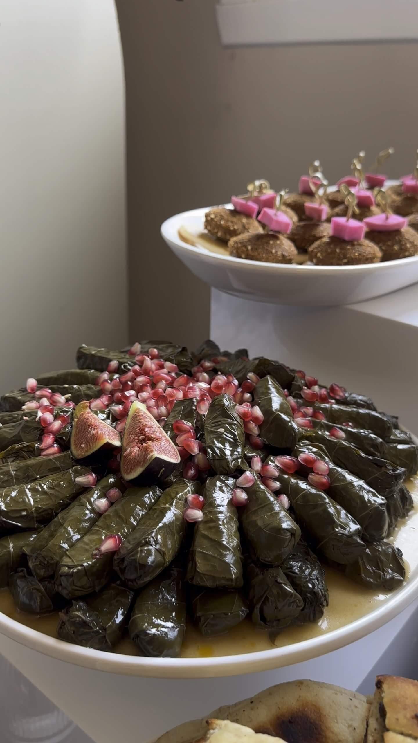 Stuffed vine leaves with pomegranate and figs on white serving dishes